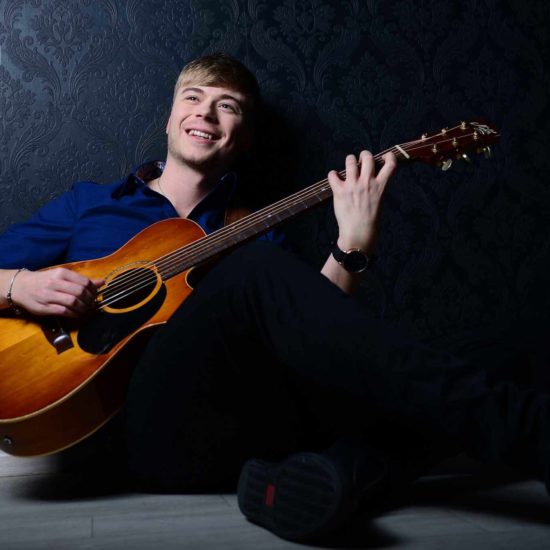 Der Gitarrist Frank Schlüter spielt sitzend auf seiner Gitarre