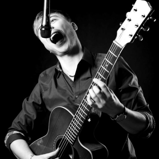 Der Gitarrist und Beatboxer Frank Schlüter spielt auf seiner Akustik-Gitarre und singt in ein Mikrofon