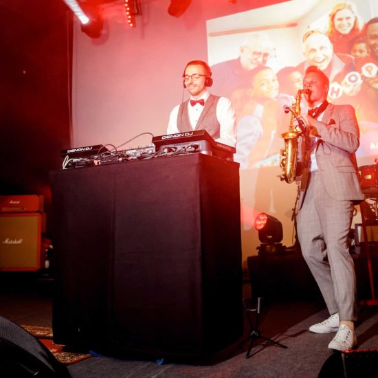 Ein DJ und ein Saxophonist spielen auf einer Party.