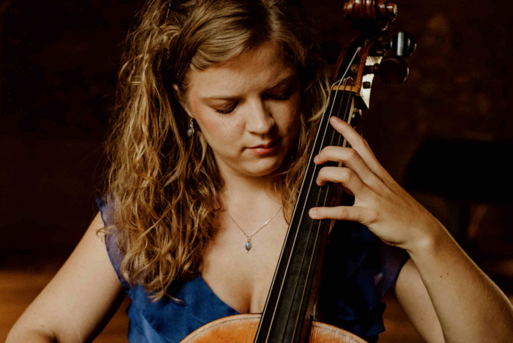 Die Musikerin Alma Stolte spielt auf ihrem Cello in einem blauen Kleid