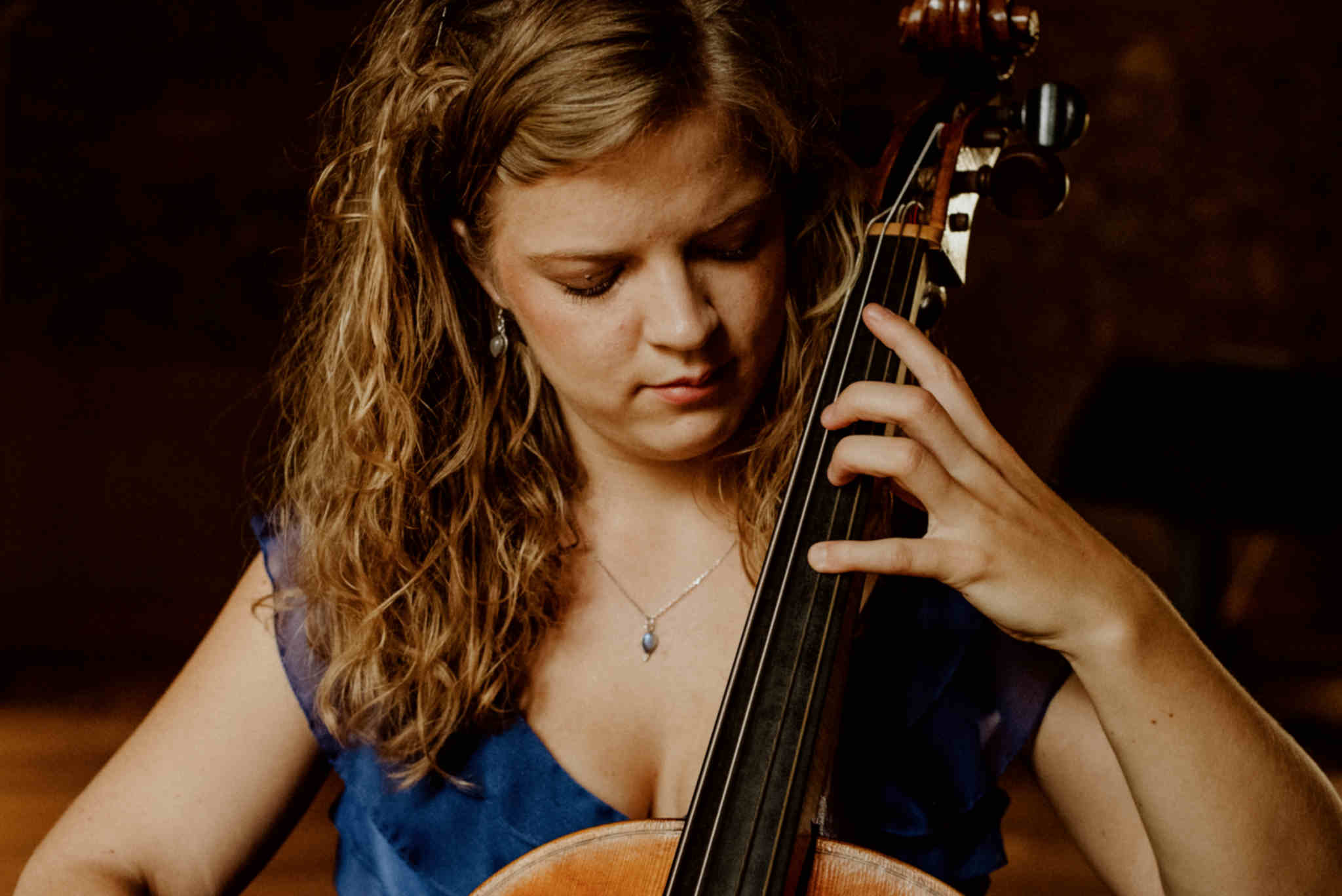 Die Musikerin Alma Stolte spielt auf ihrem Cello in einem blauen Kleid