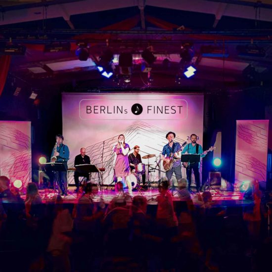 BERLINs FINEST Partyband spielt auf einer Bühne Menschen feiern davor