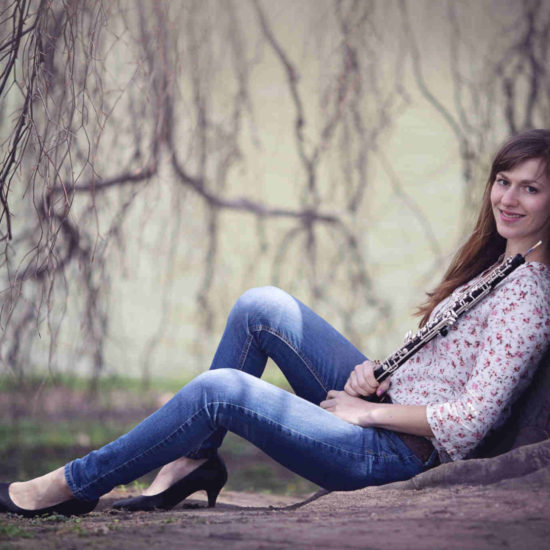 Die Dresdner Musikerin Elisabeth Beckert sitzt mit ihrer Oboe an eine Weide gelehnt
