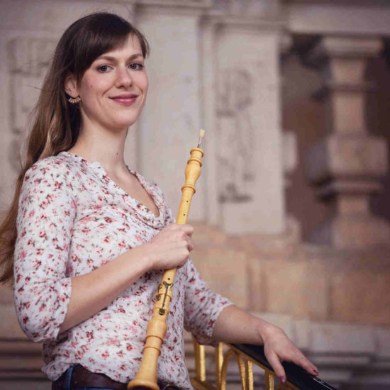 Die Dresdner Musikerin Elisabeth Beckert steht mit ihrer Barockoboe vor einem Geländer