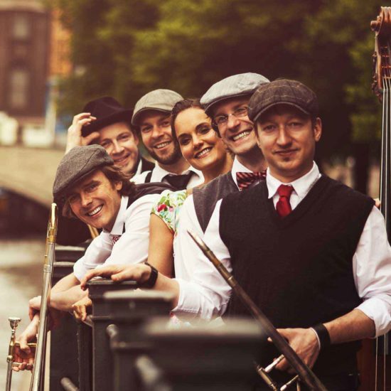 Die Musiker der Swingband German Trombone Vibration lehnen an einem Geländer