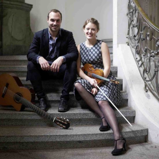 Die Musiker SARAH und LUCA sitzen mit Violine und Gitarre auf einer Treppe