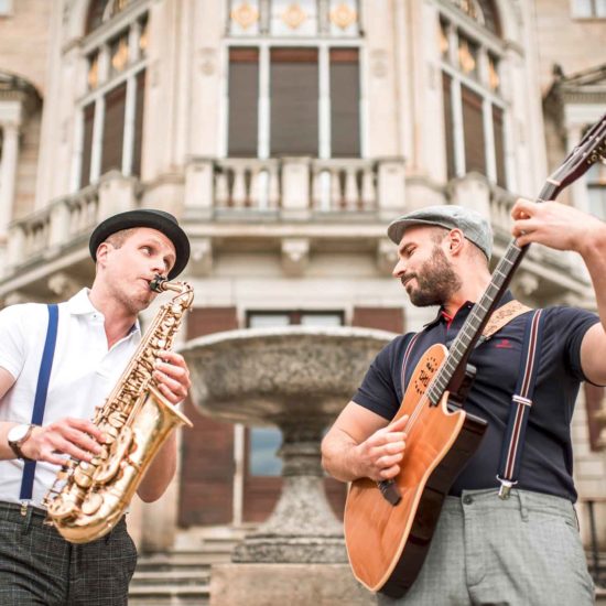 Der Saxophonist und Gitarrist des Jazzduos Schooko-Duo stehen vor Schloss Albrechtsberg in Dresden