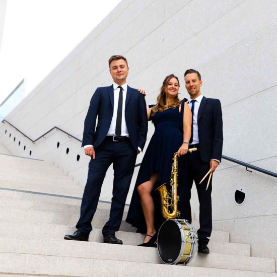 Die Saxophinistin Lina Peters posiert mit ihrem Jazztrio auf einer Treppe