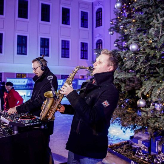 DJ mit Saxophon Kenduro&Schoof spielen vor einem Weihnachtsbaum auf einer Eisfläche