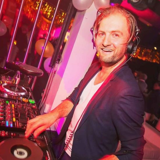 DJ Agent Twist steht an seinen Plattentellern und spielt Musik im Club