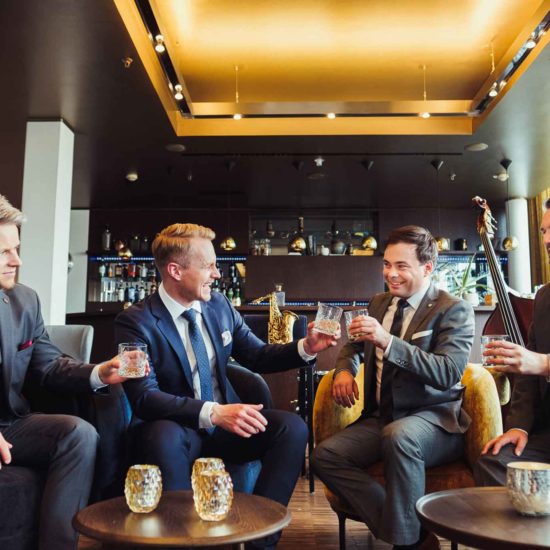 Die Hochzeitsband Swing Department sitzt in einer Hotelbar und prostet sich zu