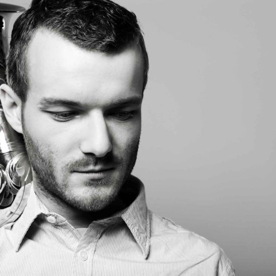 Der Saxophonist Richard Ebert hat sein Saxophon auf der Schulter und schaut nach unten