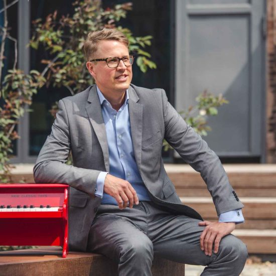 Der PIanist Moritz Töpfer sitzt un d stützt sich auf seinem Klavier auf.