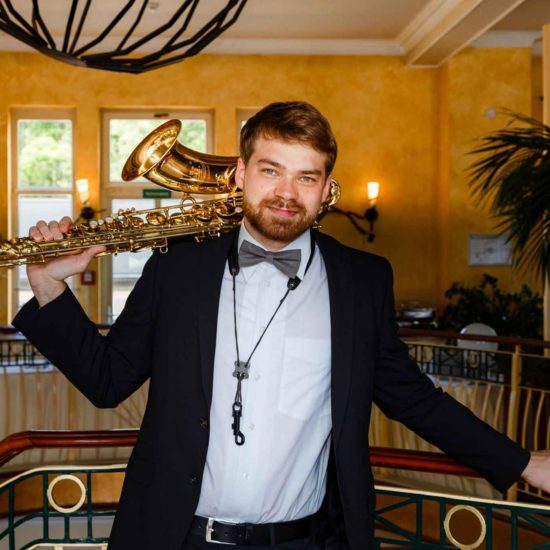 Der Saxophonist des Fingersnapper Duo trägt sein Saxophon auf der Schulter.