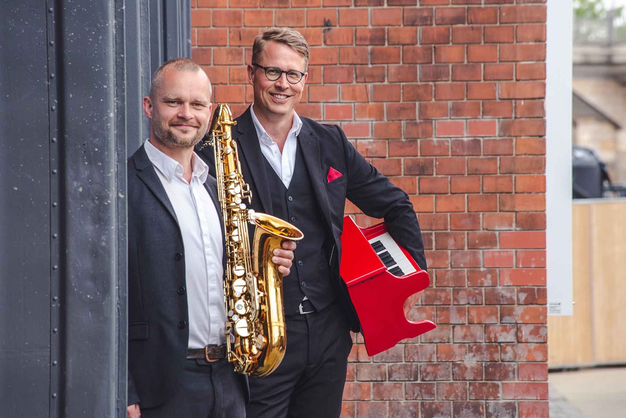 Der Saxophonist und der Pianist posieren am Kraftwerk Mitte in Dresden.